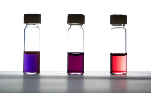 three vials of bright colored liquid: purple, maroon, and red