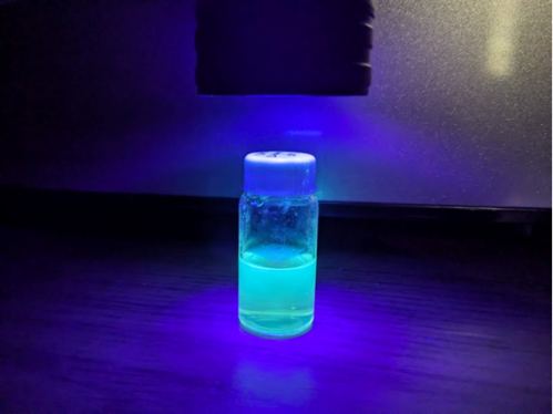 vial under blacklight glowing with fluorescent blue liquid