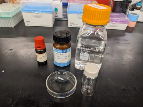 several chemical bottles and empty vial arrayed on a lab bench