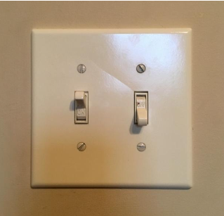 photo of a panel with two light switches, one up and one down