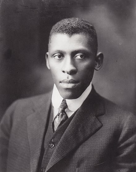 Black & white portrait of a young Black man looking serious in suit and tie